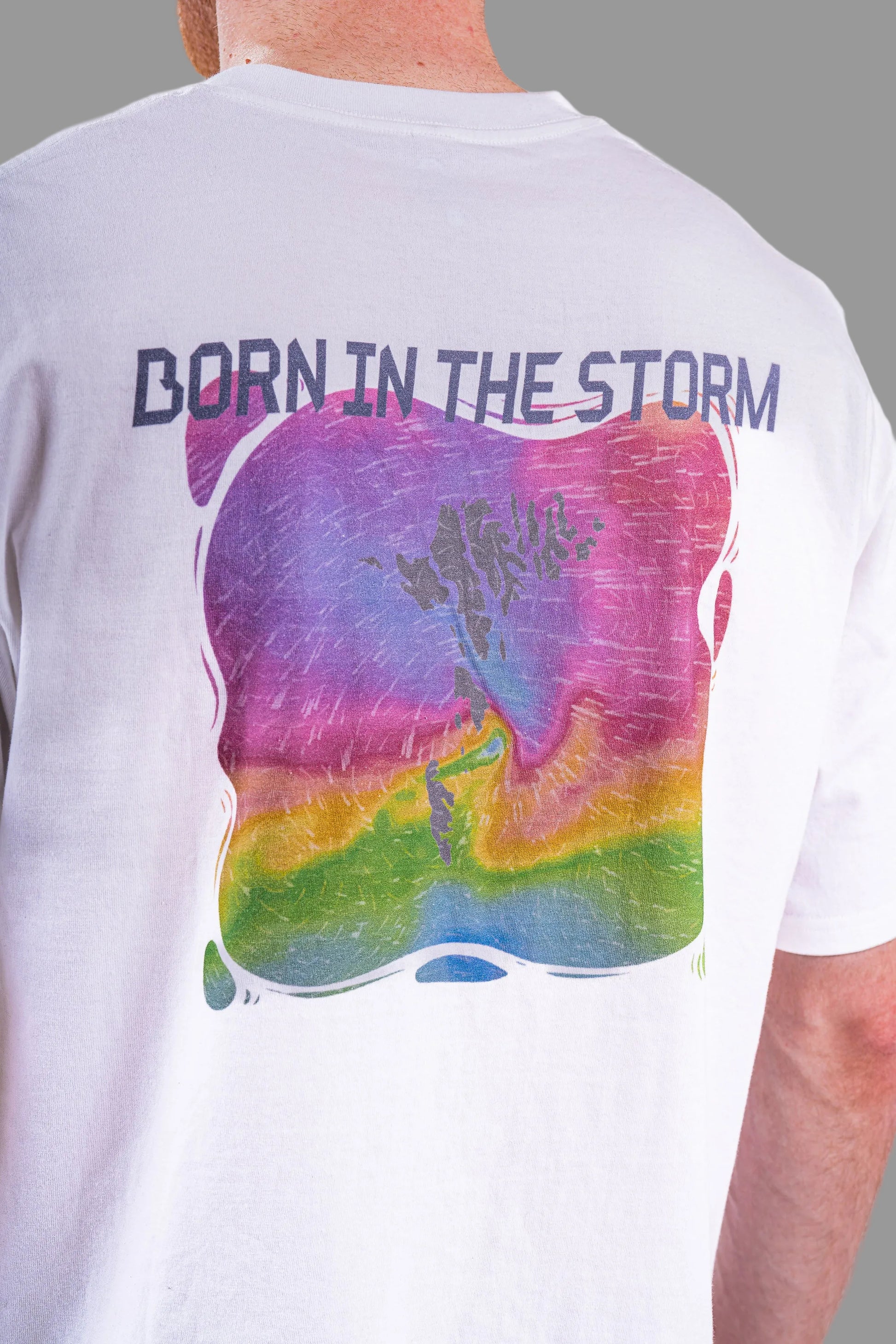 White t-shirt with colorful graphic and 'Born in the Storm' text on a plain background