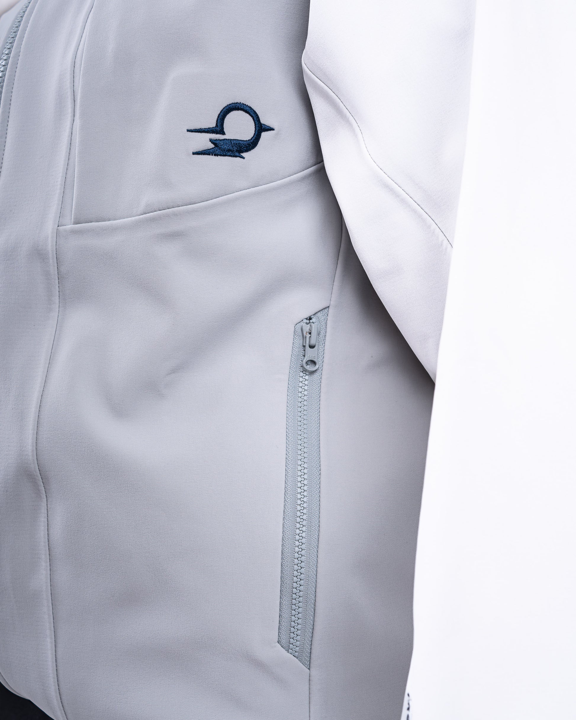 Close-up of a gray jacket with a zipper and a logo on a white background
